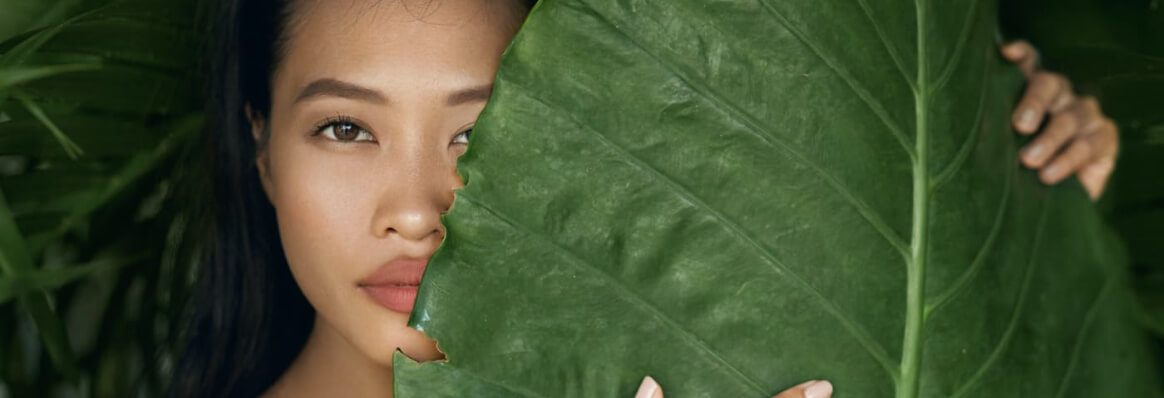 Beautiful woman holding a palm leaf up to her face